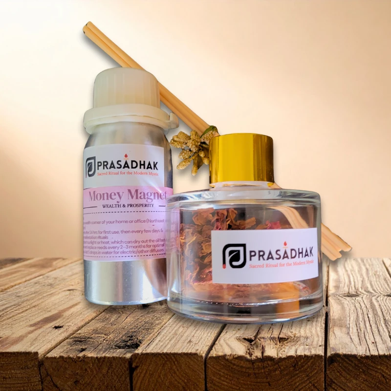Money Magnet reed diffuser set: metal bottle with pink label beside a glass jar of dried botanicals, gold cap, on wood.