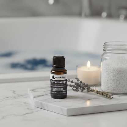 A small amber glass bottle labeled Prasadhak Dreamscape sits on a white marble tray in a spa-like setting