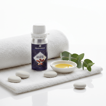 Prasadhak Cold-pressed Argan Oil on white towel with ceramic bowl and eucalyptus - bright spa aesthetic