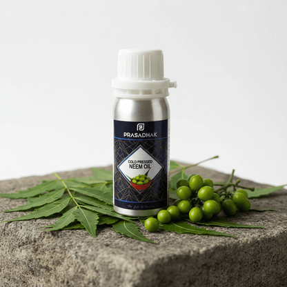 A bottle of Prasadhak Cold-Pressed Neem Oil placed on a stone surface with neem leaves and green berries around it, against a clean white background.