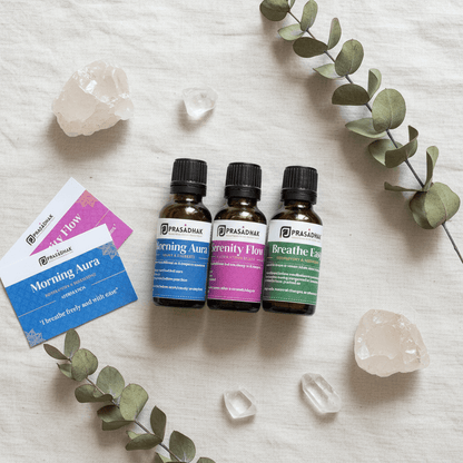 Three small amber essential oil bottles labeled Prasadhak (Morning Aura, Serenity Flow, and Breathe Easy)