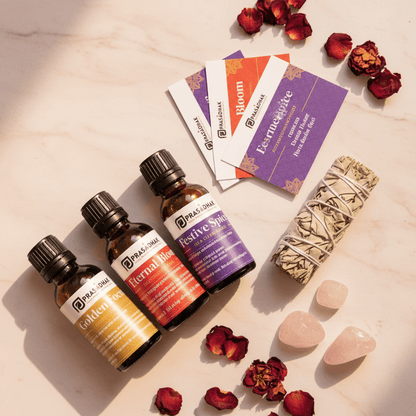 Three essential oil bottles labeled Prasadhak Golden Focus, Eternal Bloom, and Festive Spice on a light marble surface.